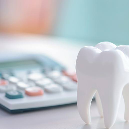 Model tooth next to calculator on desk