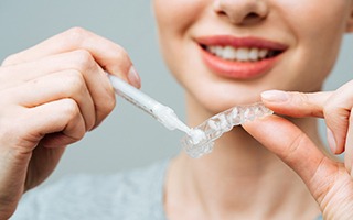 Woman applying whitening gel to custom-fitted applicator tray